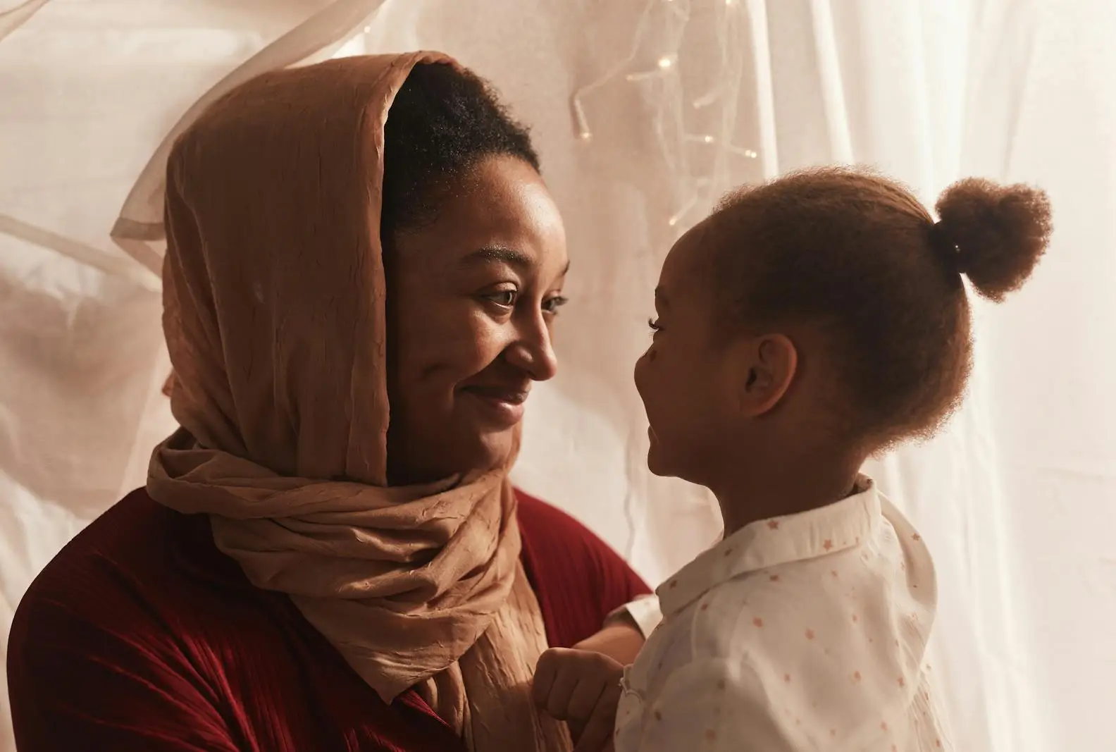 Muslim mother in hijab reading with her child in a warm home environment